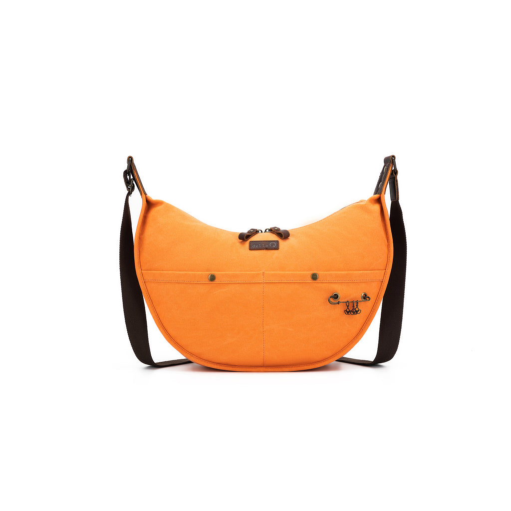 Bright orange canvas maker’s bag with signature crescent shape. 
