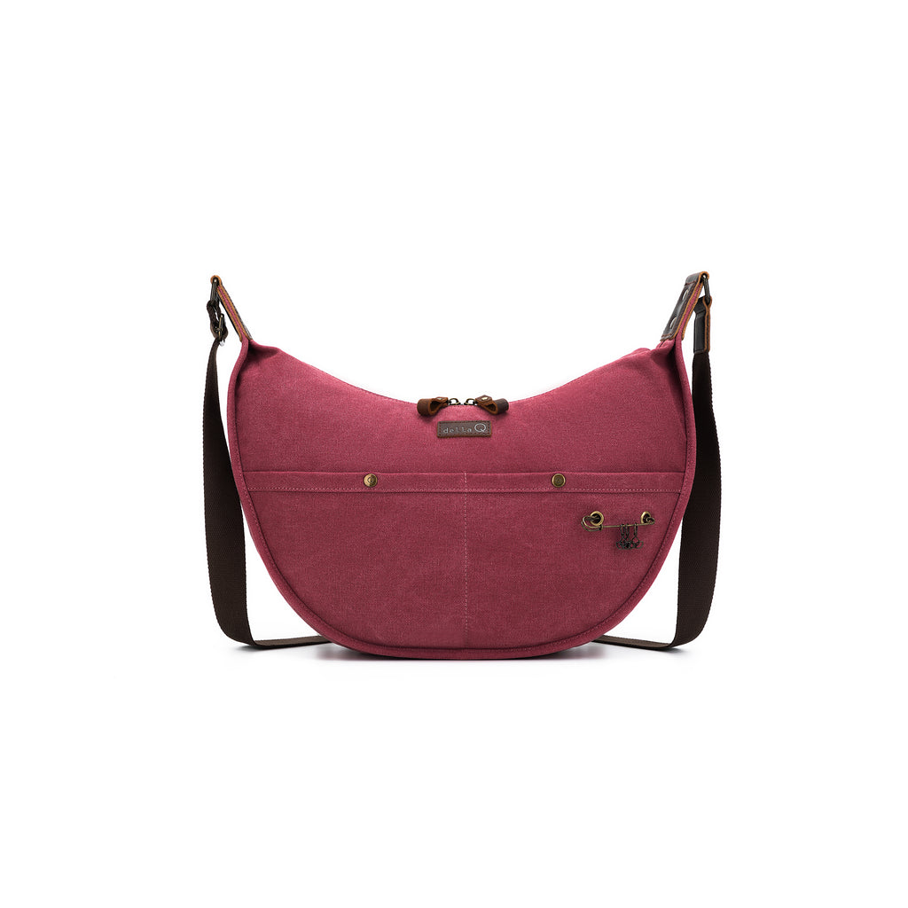 A rich maroon-hued project bag with della Q leather label, front pockets, built-in yarn cutter, and contrast brown strap.